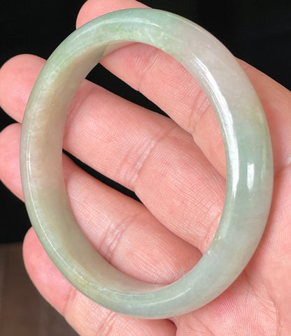 Close-up of fine crystalline texture and vibrant apple green hues on milky white jadeite bangle