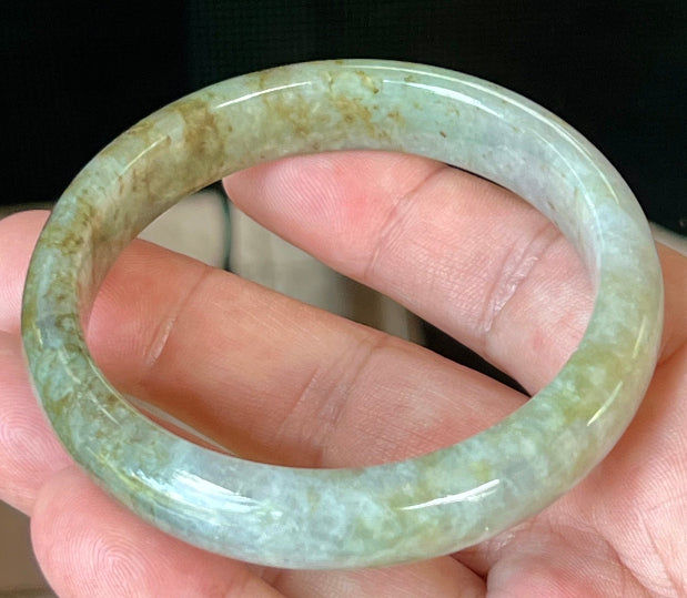 Close-up of fine crystalline texture and golden honey hues on icy grayish white jadeite bangle