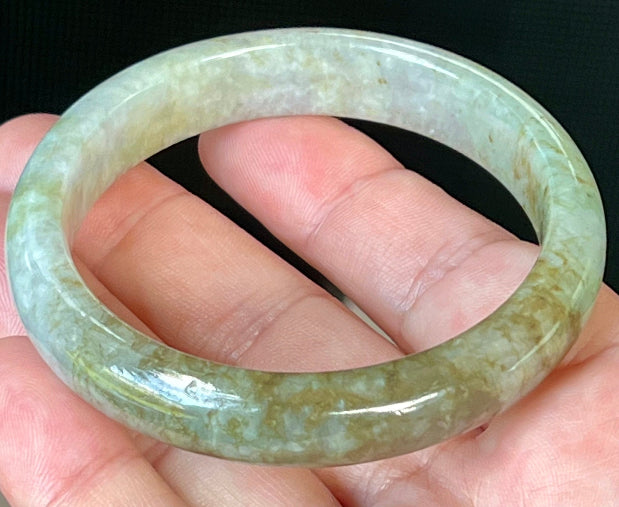 Close-up of fine crystalline texture and golden honey hues on icy grayish white jadeite bangle