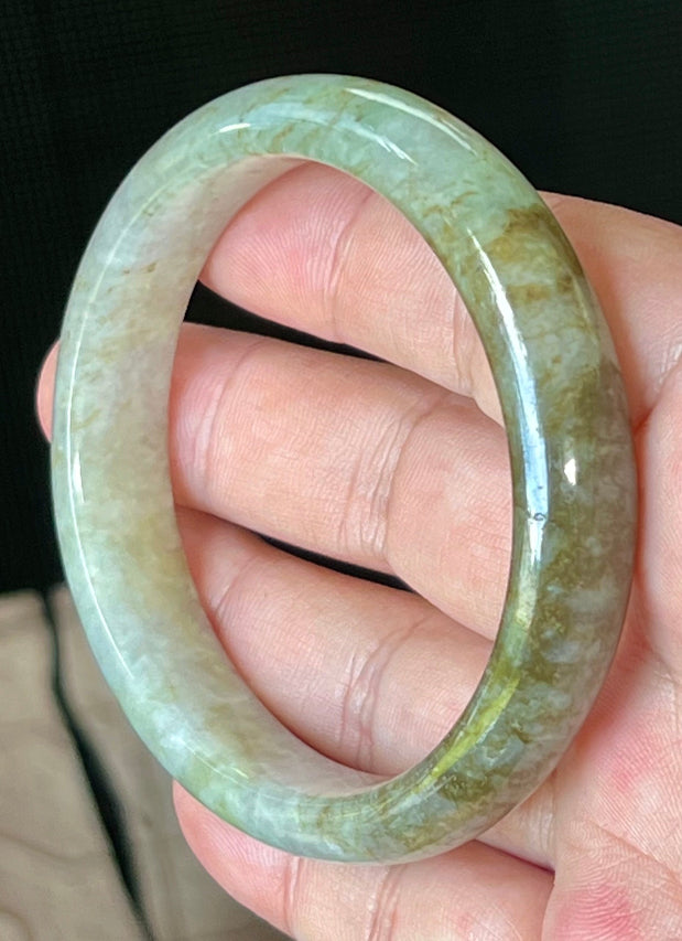 Close-up of fine crystalline texture and golden honey hues on icy grayish white jadeite bangle