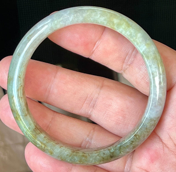 Close-up of fine crystalline texture and golden honey hues on icy grayish white jadeite bangle