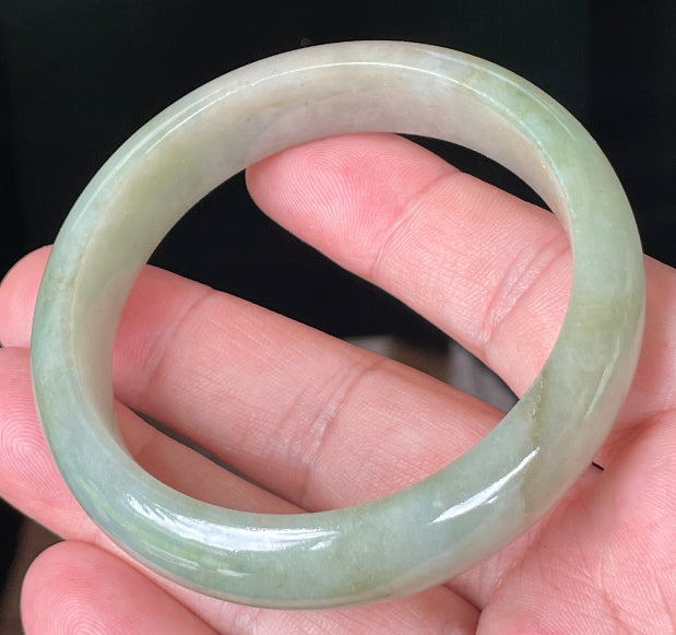 Close-up of fine crystalline texture and moss-in-the-snow effect on icy apple green jadeite bangle