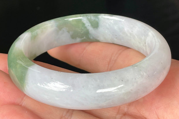 Close-up of fine crystalline texture and moss in the snow pattern on icy greyish white jadeite bangle
