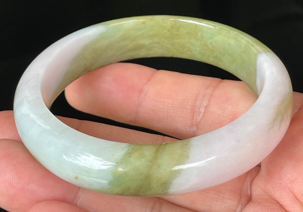 Close-up of fine crystalline texture and rich forest green tones on icy apple green jadeite bangle