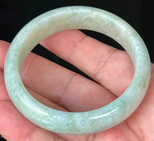 Close-up of fine crystalline texture and spicy apple green hues on milky white jadeite bangle