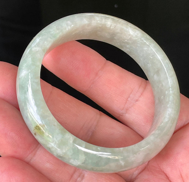 Close-up of fine crystalline texture and vibrant apple green hues on icy milky white jadeite bangle
