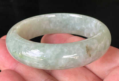 Close-up of fine crystalline texture and vibrant apple green hues on icy milky white jadeite bangle