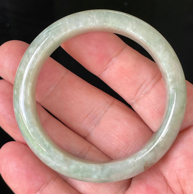 Close-up of fine crystalline texture and vibrant apple green hues on icy milky white jadeite bangle