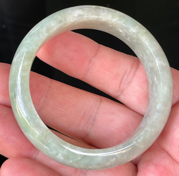 Close-up of fine crystalline texture and vibrant apple green hues on icy milky white jadeite bangle