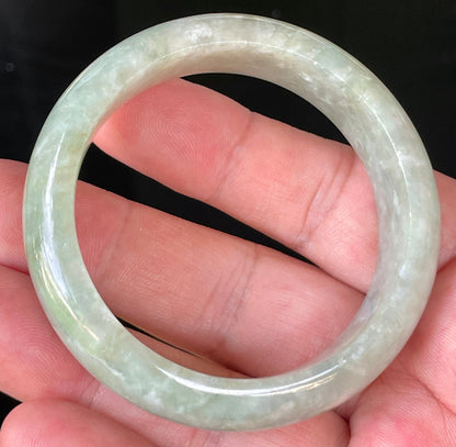 Close-up of fine crystalline texture and vibrant apple green hues on icy milky white jadeite bangle