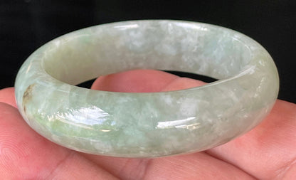 Close-up of fine crystalline texture and vibrant apple green hues on icy milky white jadeite bangle