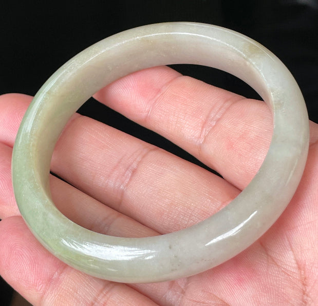 Close-up of fine crystalline texture and warm brown hues on icy apple green jadeite bangle
