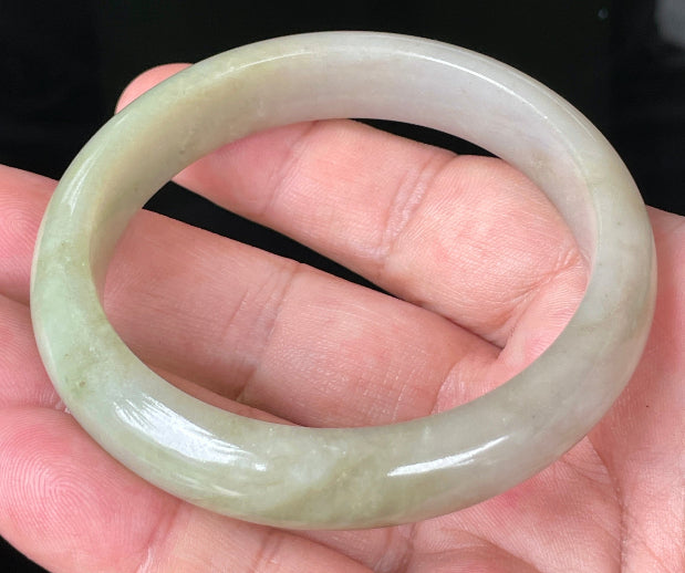 Close-up of fine crystalline texture and warm brown hues on icy apple green jadeite bangle