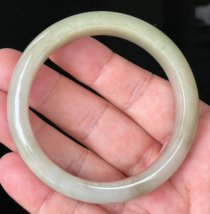 Close-up of fine crystalline texture and warm brown hues on icy apple green jadeite bangle