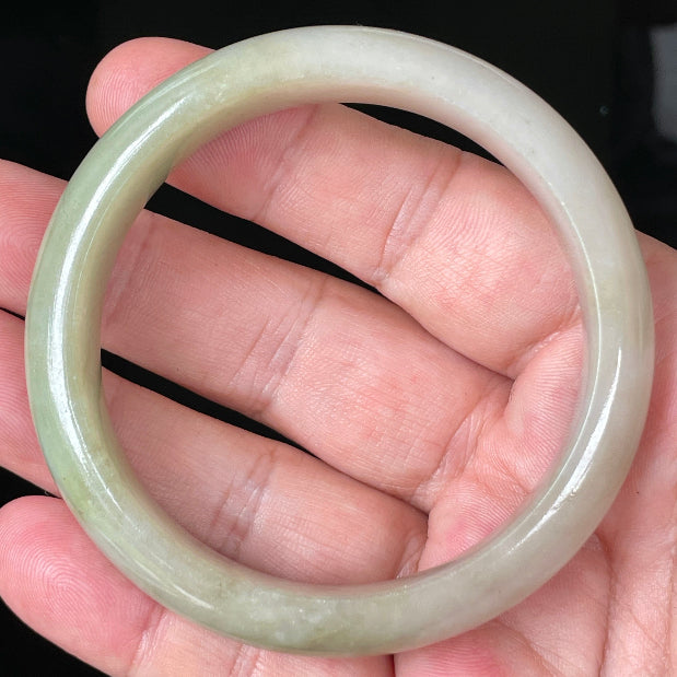 Close-up of fine crystalline texture and warm brown hues on icy apple green jadeite bangle