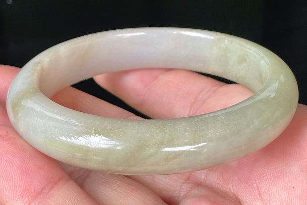 Close-up of fine crystalline texture and warm brown hues on icy apple green jadeite bangle