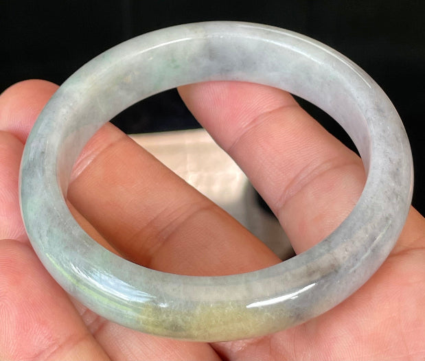 Close-up of fine crystalline texture and warm honey hues on icy grey and milky white jadeite bangle