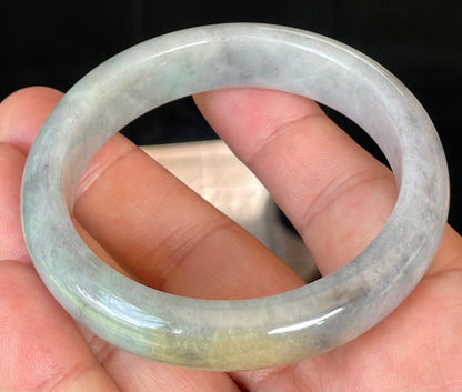 Close-up of fine crystalline texture and warm honey hues on icy grey and milky white jadeite bangle