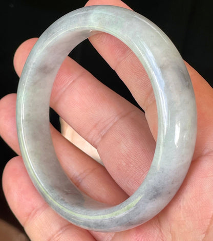 Close-up of fine crystalline texture and warm honey hues on icy grey and milky white jadeite bangle