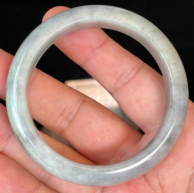 Close-up of fine crystalline texture and warm honey hues on icy grey and milky white jadeite bangle