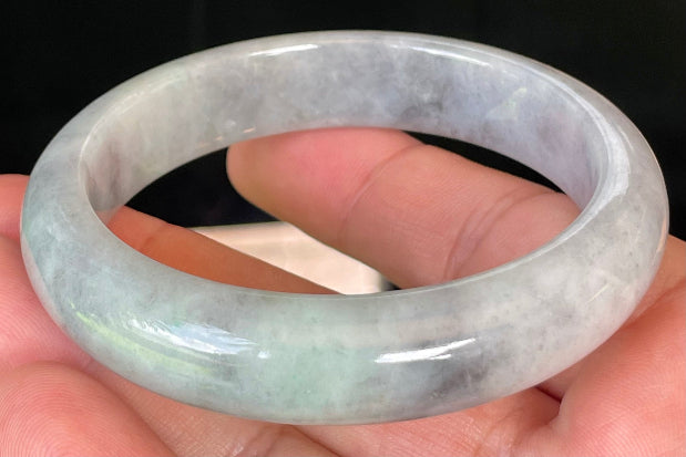 Close-up of fine crystalline texture and warm honey hues on icy grey and milky white jadeite bangle