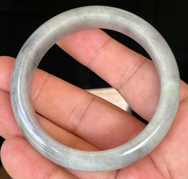 Close-up of fine crystalline texture and warm honey hues on icy grey and milky white jadeite bangle