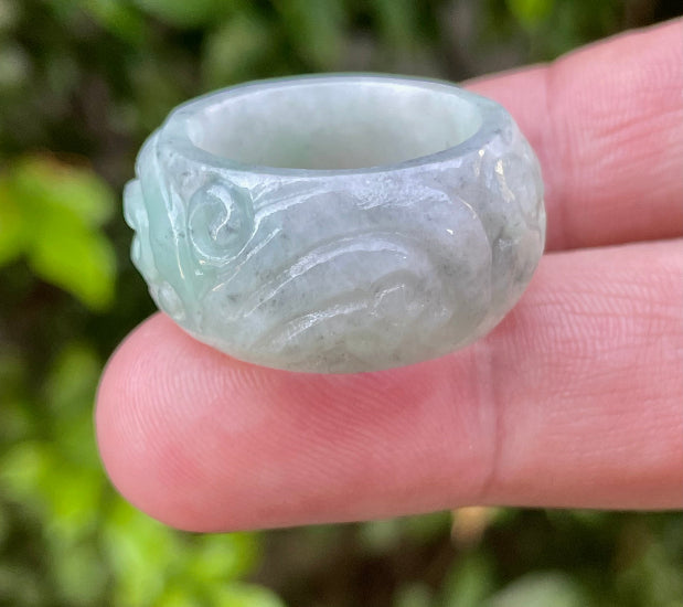 Close-up of graceful hand-carved swirl motif and fine crystalline texture on an icy bluish apple green Burmese jade ring