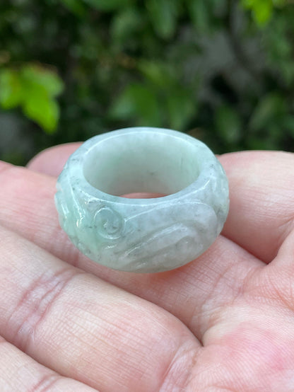 Close-up of graceful hand-carved swirl motif and fine crystalline texture on an icy bluish apple green Burmese jade ring