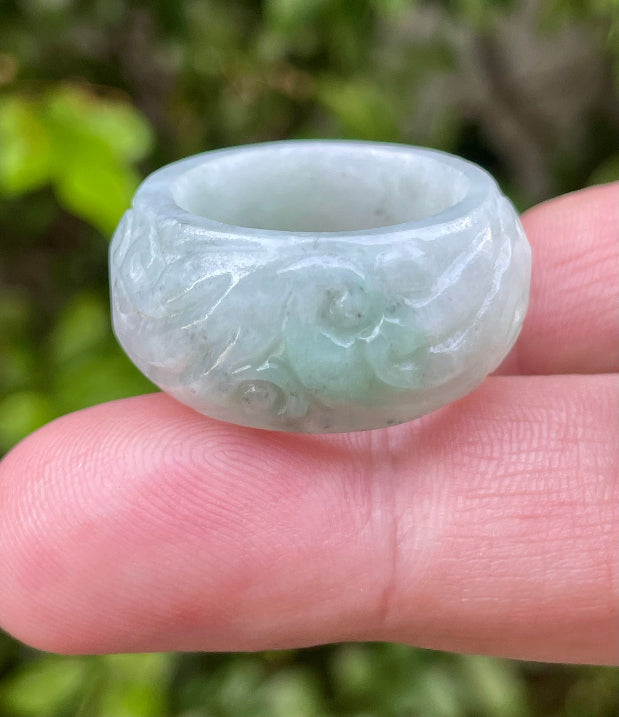Close-up of graceful hand-carved swirl motif and fine crystalline texture on an icy bluish apple green Burmese jade ring