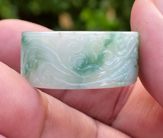 Close-up of continuous flowing swirl patterns and fine-grained texture on an icy imperial green Burmese jade ring
