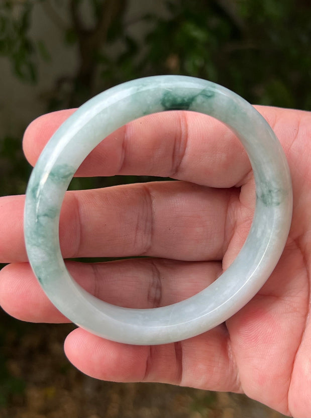 Close-up of moss in snow and emerald green patterns on icy green jadeite bangle