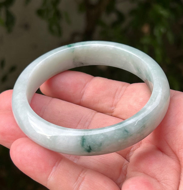 Close-up of moss in snow and emerald green patterns on icy green jadeite bangle