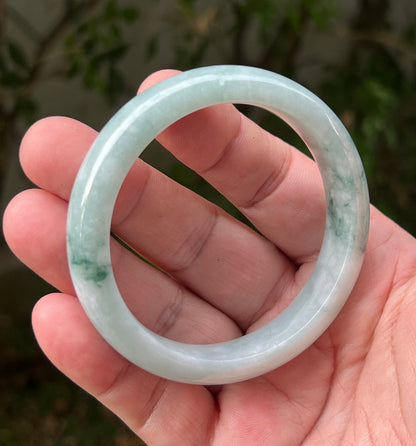 Close-up of moss in snow and emerald green patterns on icy green jadeite bangle