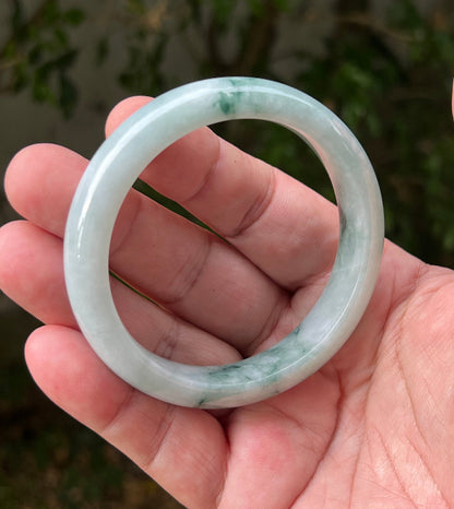 Close-up of moss in snow and emerald green patterns on icy green jadeite bangle