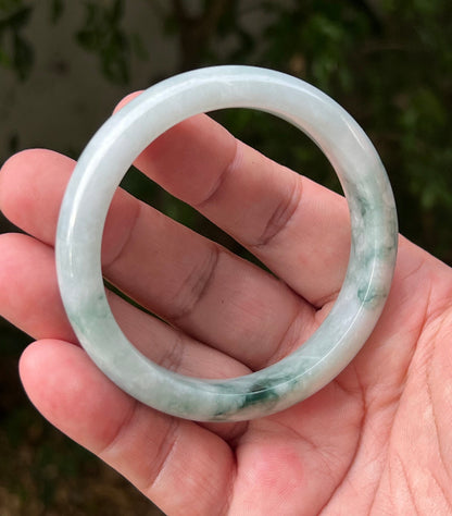 Close-up of moss in snow and emerald green patterns on icy green jadeite bangle