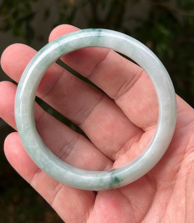 Close-up of moss in snow and emerald green patterns on icy green jadeite bangle