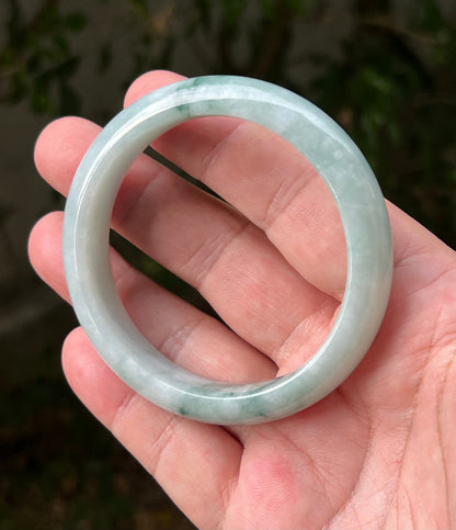 Close-up of moss in snow and emerald green patterns on icy green jadeite bangle