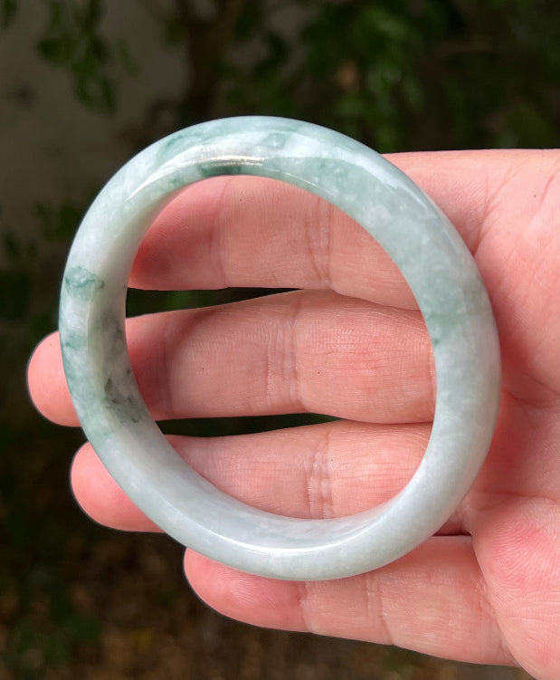 Close-up of moss in snow and emerald green patterns on icy green jadeite bangle