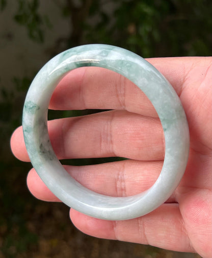 Close-up of moss in snow and emerald green patterns on icy green jadeite bangle