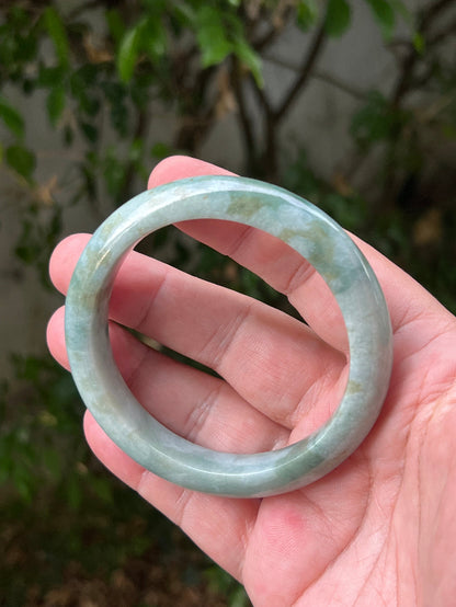 Close-up of natural moss green cloud formations on icy seafoam jadeite bangle