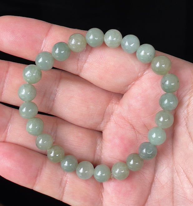Round 8.2mm natural Type A Burmese jade beads showing gentle translucency and icy green colors on the wrist