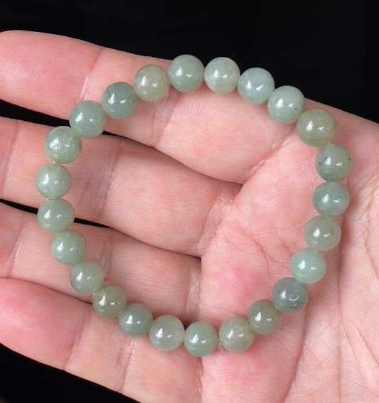 Round 8.2mm natural Type A Burmese jade beads showing gentle translucency and icy green colors on the wrist