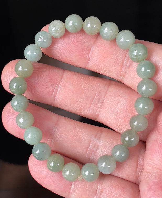 Round 8.2mm natural Type A Burmese jade beads showing gentle translucency and icy green colors on the wrist