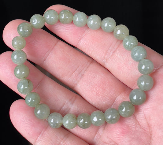 Round 8.2mm natural Type A Burmese jade beads showing gentle translucency and icy green colors on the wrist