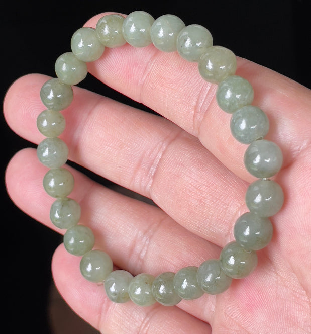 Round 8.2mm natural Type A Burmese jade beads showing gentle translucency and icy green colors on the wrist