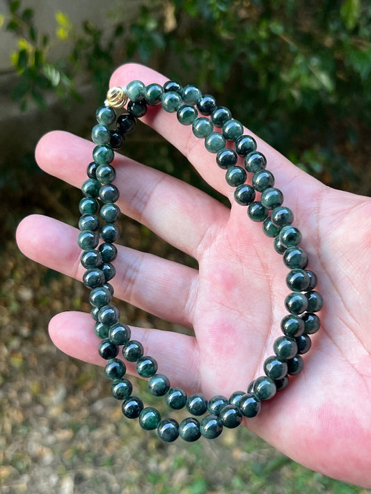 Close-up of 7.6mm Certified Grade A Burmese jadeite beads featuring beautiful icy deep forest and apple green hues, item JN096