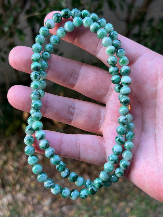 Close-up of 6.8mm Certified Grade A Burmese jadeite beads featuring beautiful icy imperial and apple green hues, item JN088