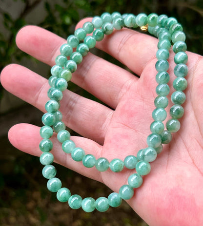 Close-up of 7.5mm Certified Grade A Burmese jadeite beads featuring a beautiful icy imperial and apple green "Moss in the Snow" effect, item JN004