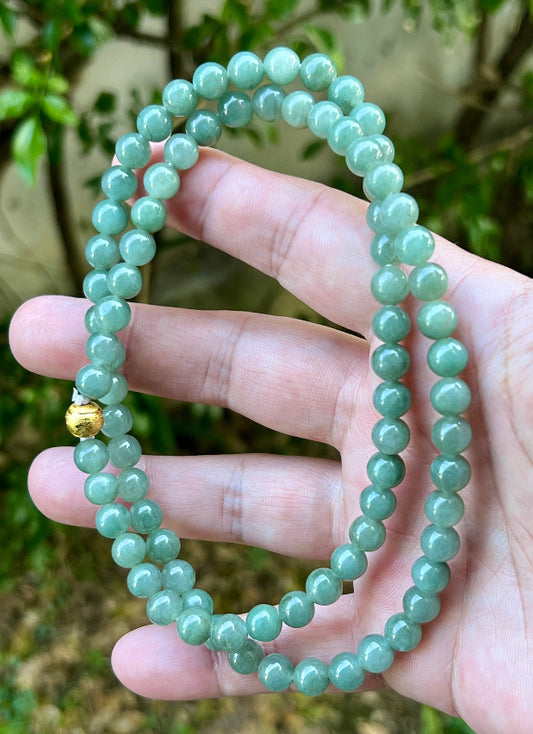 Close-up of 7.5mm Certified Grade A Burmese jadeite beads featuring beautiful icy imperial white and apple green hues, item JN019
