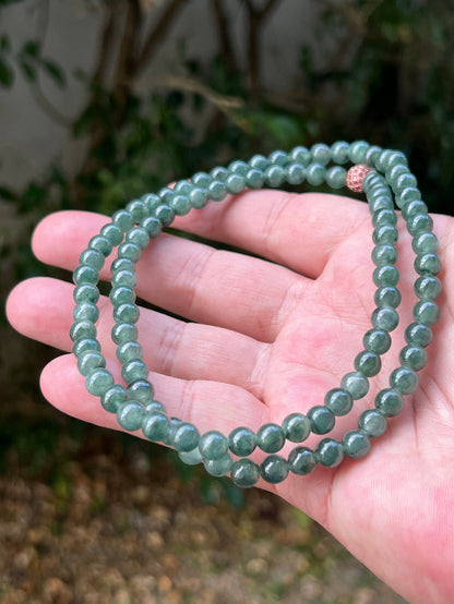 Close-up of 6.4mm Certified Grade A Burmese jadeite beads featuring beautiful icy imperial and deep emerald green hues, item JN092